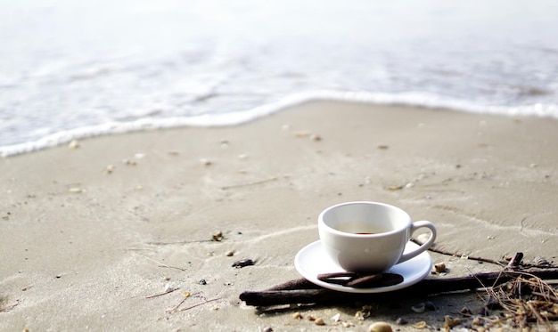 Zdjęcie zbliżenie filiżanki kawy na brzegu na plaży