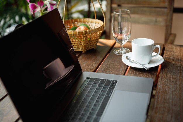 Zbliżenie filiżanki kawy przez laptop na stole