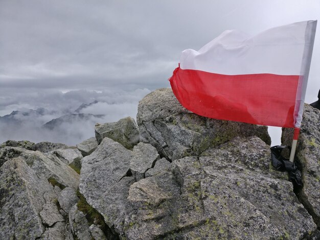 Zdjęcie zbliżenie flagi na skale na tle nieba