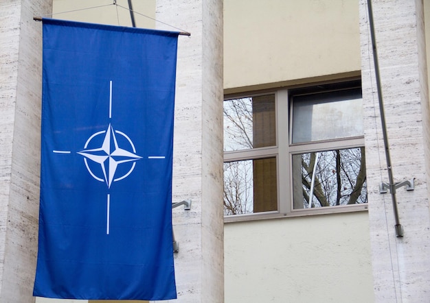 Zbliżenie flagi NATO wiszącej na budynku pod słońcem