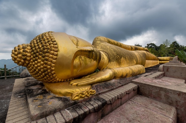 Zbliżenie gigantycznej złotej statuy śpiącego Buddy na szczycie wzgórza pod pochmurnym niebem Samui Tajlandia