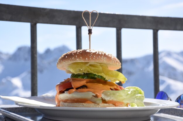 Zdjęcie zbliżenie hamburgera podawanego na talerzu na balkonie