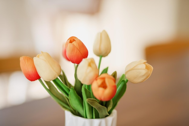 Zbliżenie i selektywne skupienie plastikowego tulipana na białym wazonie na stole