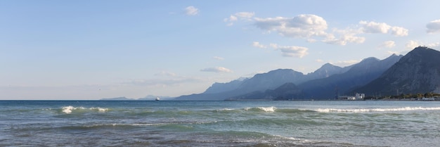 Zbliżenie kamienistej plaży z zachmurzonym niebieskim niebem na mglistych górach w tle górski krajobraz