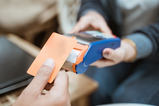 Zbliżenie karty kredytowej w pobliżu urządzenia do elektronicznego przechwytywania danych podczas zakupów w sklepie