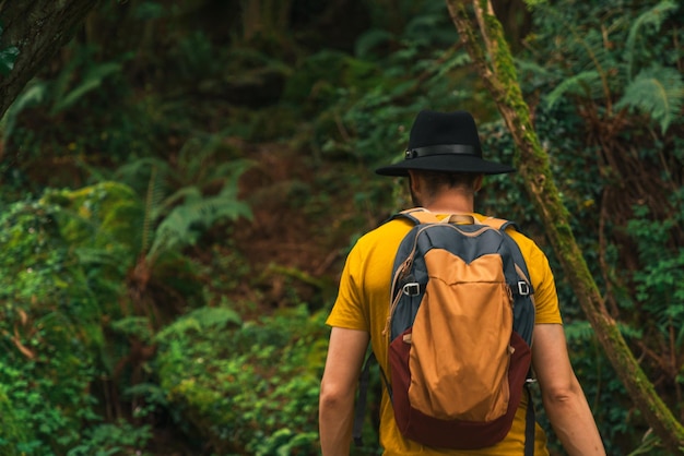 Zbliżenie kaukaski młody człowiek z żółtą koszulą spacerujący po lesie