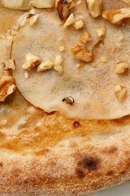 Zbliżenie kawałek pizzy z gorgonzolą, pokrojoną gruszką i orzechami włoskimi