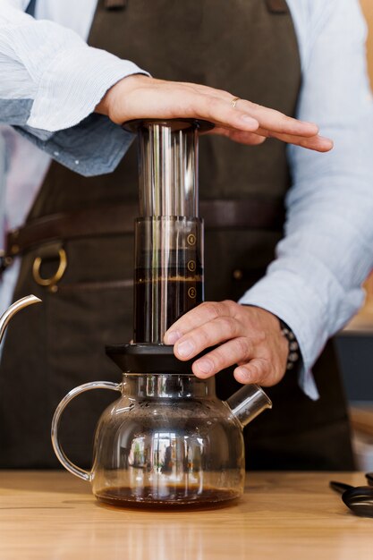 Zbliżenie kawy Aeropress: barista naciśnij urządzenie, a krople kawy wlewają aeropress do garnka