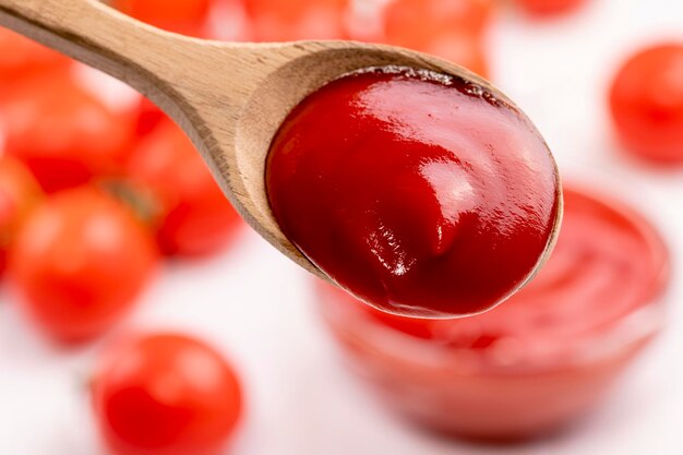 Zbliżenie ketchupu i pomidorów na drewnianym tle Łyżka ketchupu Selektywne ustawianie ostrości