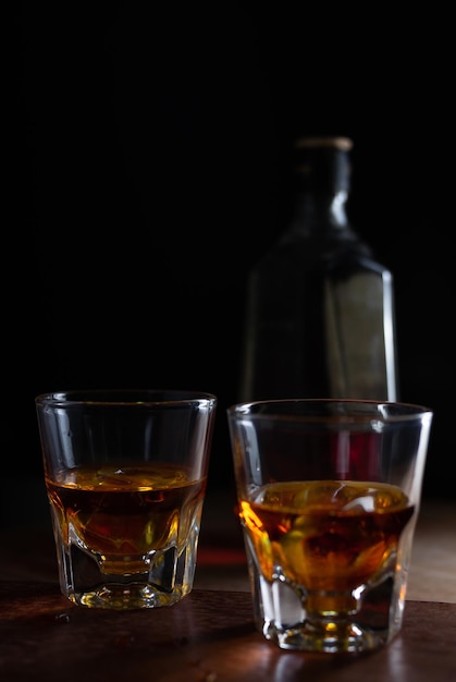 Zbliżenie kieliszków whisky na stole na czarnym tle