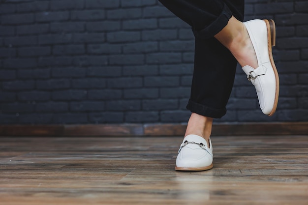 Zbliżenie kobiece nogi w czarnych spodniach i skórzanych beżowych mokasynach Nowa wiosennoletnia kolekcja damskich skórzanych butów 2022