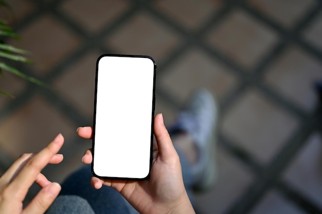 Zbliżenie kobiecej dłoni trzymającej makietę białego ekranu smartfona na rozmytym tle