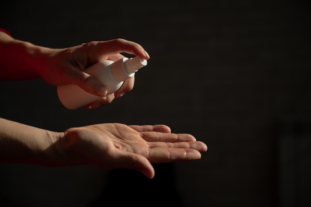 Zbliżenie kobiecych dłoni z antyseptycznym sprayem Kobieta w celu zapobiegania koronawirusowi rozpyla środek przeciwbakteryjny w dłoni