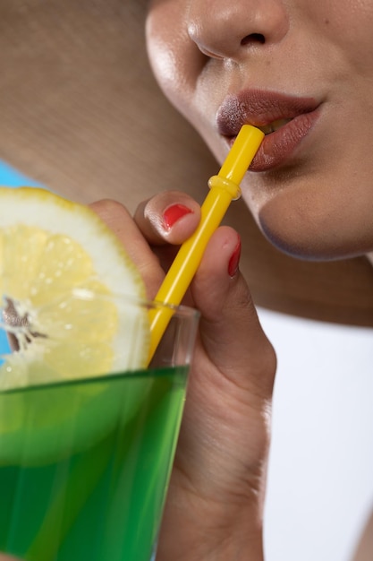 Zdjęcie zbliżenie kobiecych ust podczas picia zielonego zimnego napoju alkoholowego przez słomkę