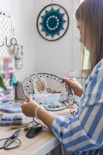 Zdjęcie zbliżenie kobieta artysta tworząc ręcznie robione akcesoria dreamcatcher użyj kolorowych koralików amulet na szczęście