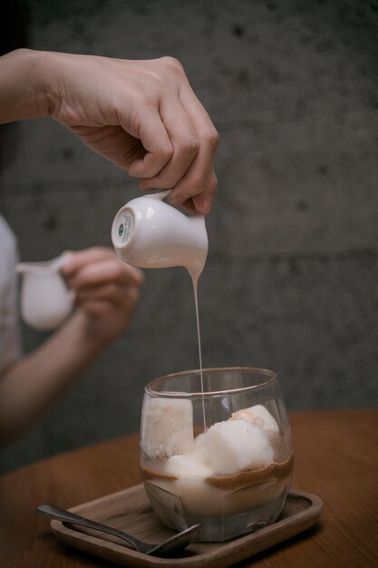 Zbliżenie Kobieta Dłonie wlewa mleko do zimnej herbaty lub kawy z cytryny do zimnego menu zaparzania