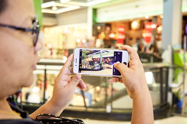 Zdjęcie zbliżenie kobiety fotografującej telefonem komórkowym w centrum handlowym