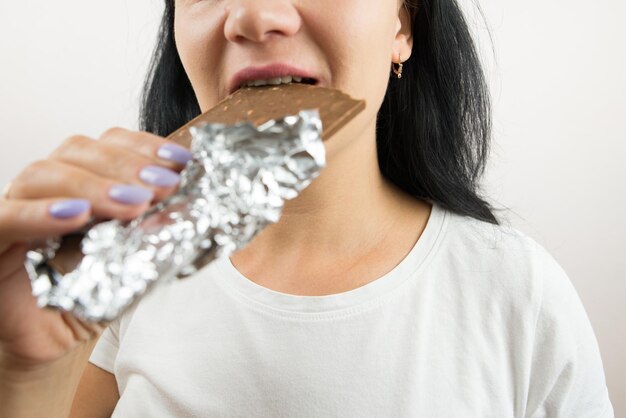 Zdjęcie zbliżenie kobiety jedzącej tabliczkę czekolady