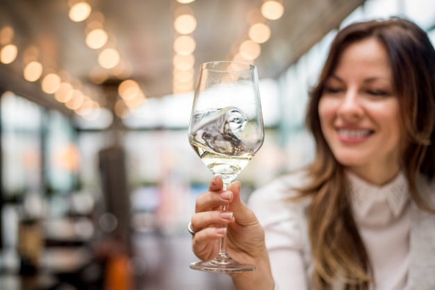 Zbliżenie kobiety mienia szkło wino w cukiernianej restauraci.