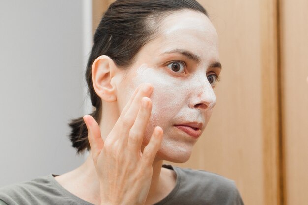 Zbliżenie kobiety nakładającej maskę na twarz w domu