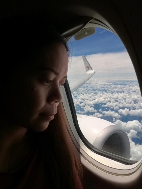 Zdjęcie zbliżenie kobiety patrzącej przez okno samolotu