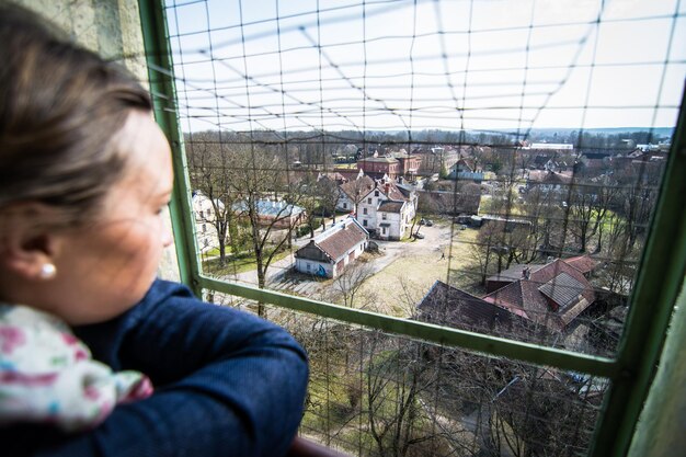 Zbliżenie kobiety patrzącej przez okno