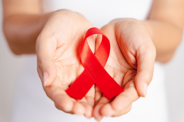 Zbliżenie Kobiety Ręka Trzyma Czerwoną Wstążkę Hiv, światowa Wstążka Dzień Aids świadomości. Pojęcie Opieki Zdrowotnej I Medycyny.