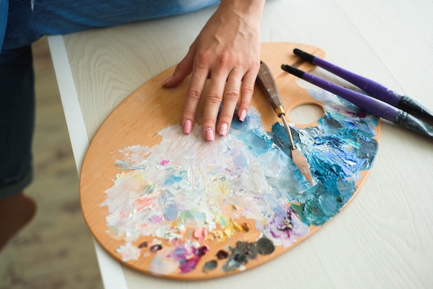 Zbliżenie kobiety ręki mieszanka maluje z muśnięciem w palecie w sztuki klasie