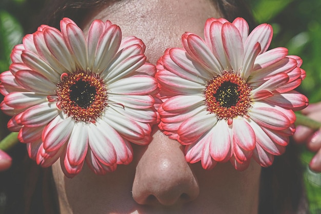 Zbliżenie kobiety trzymającej kwiaty na twarzy