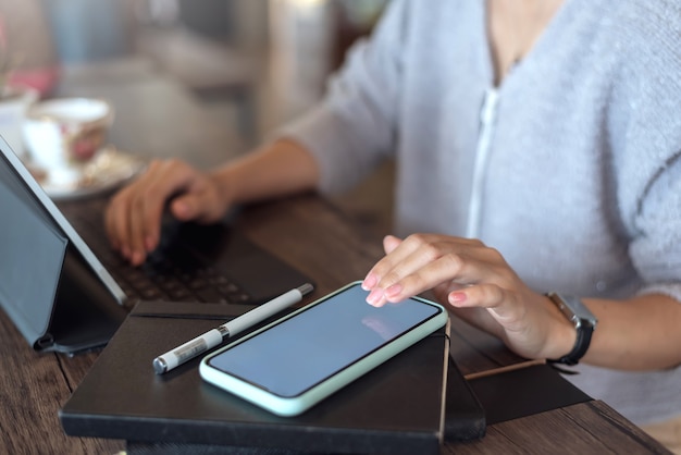 Zbliżenie kobiety trzymającej telefon komórkowy z pustym białym ekranem.