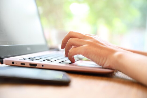 Zdjęcie zbliżenie kobiety używającej laptopa na stole