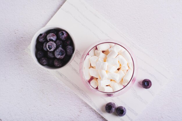 Zdjęcie zbliżenie koktajlu z jogurtem jagodowym i piankami marshmallow w szklance na widoku z góry