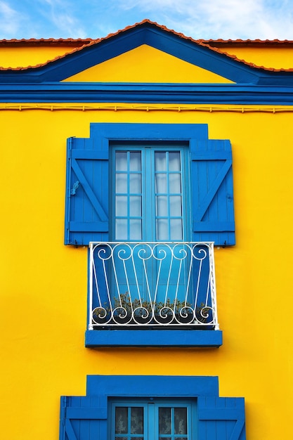Zbliżenie kolorowa portugalska żółta fasada domu ze starymi niebieskimi oknami i drewnianymi okiennicami w portugalskim mieście Europa Koncepcja podróży i architektury Vertical