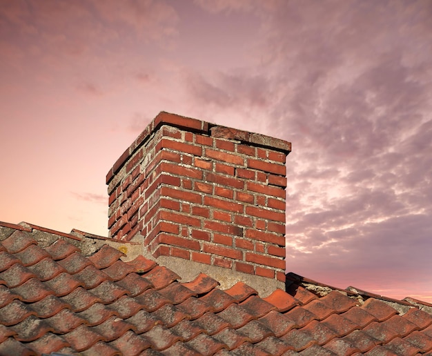 Zbliżenie komina na starym domu z czerwonej cegły z kopią przestrzeni nieba Detale architektoniczne zabytkowego stalowego dachu na budynku mieszkalnym Kamienny projekt zewnętrzny domowego pieca bez dymu