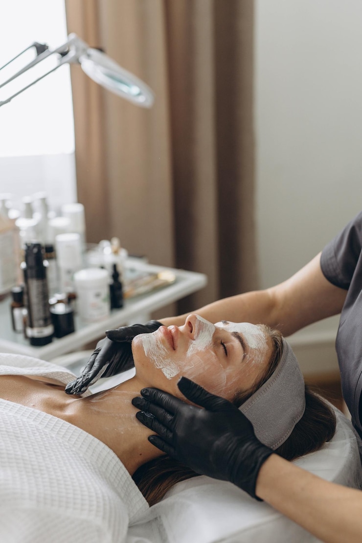 Zdjęcie zbliżenie kosmetologa robiącego maskę twarzy dla klientki w salonie dermatologia koncepcja piękna