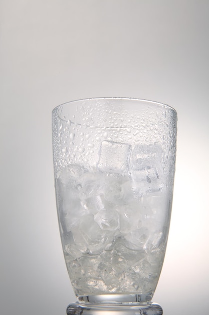 Zbliżenie kostki lodu w szklance na białe tło