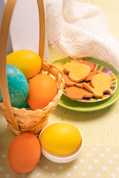 Zbliżenie kosz z Wielkanocnymi barwionymi jajkami i talerzem z ciastkami