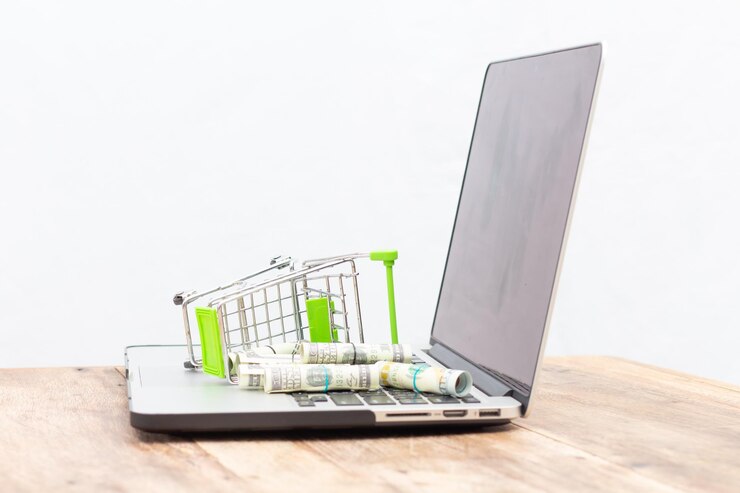 Zdjęcie zbliżenie koszyka na zakupy i papierowego pieniądza na laptopie