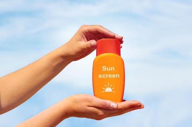 Zbliżenie kremu z filtrem przeciwsłonecznym w kobiecych rękach na plaży