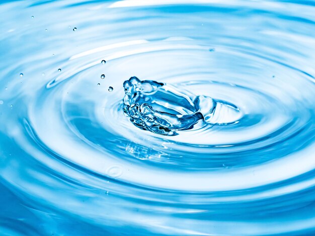 Zdjęcie zbliżenie kropli spadającej na niebieską wodę