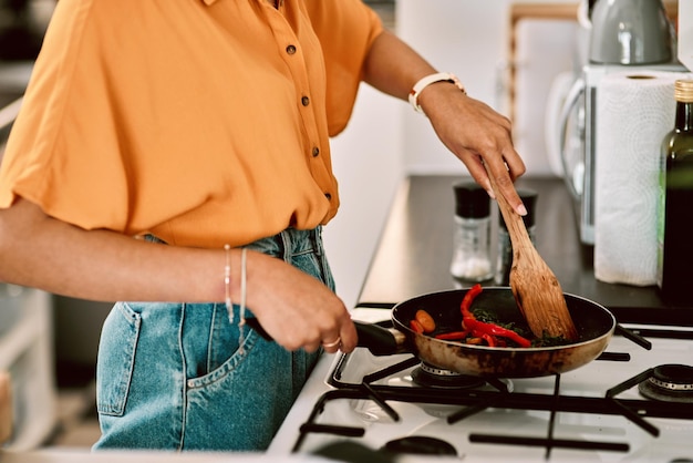 Zbliżenie kuchni i ręce kobiety gotują z patelnią na obiad obiad lub kolację w mieszkaniu Odżywianie i kobieta przygotowująca zdrowe wegetariańskie lub dietetyczne jedzenie lub posiłek na kuchence w swoim domu