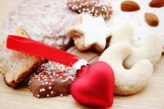 Zdjęcie zbliżenie kulki w kształcie serca przy świątecznych ciasteczkach na stole