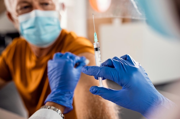 Zbliżenie lekarza szczepiącego starszego mężczyznę z powodu pandemii COVID19