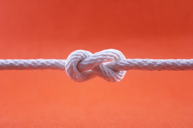 Zdjęcie zbliżenie liny przywiązanej do metalu na pomarańczowym tle
