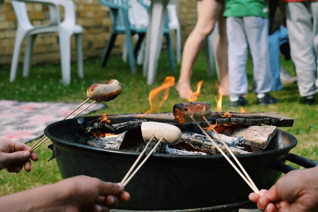 Zdjęcie zbliżenie ludzi przygotowujących jedzenie na grillu