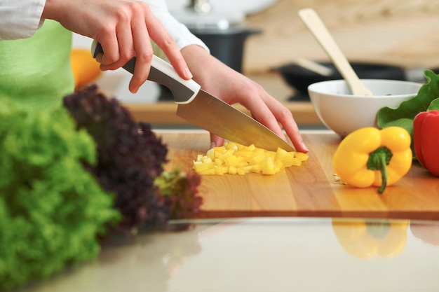 Zbliżenie ludzkich rąk gotowanie sałatka warzywna w kuchni na szklanym stole z odbicia. Zdrowy posiłek i koncepcja wegetariańska