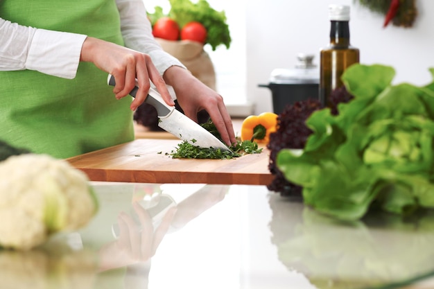 Zbliżenie ludzkich rąk gotowanie sałatki warzywnej w kuchni na szklanym stole z odbicia
