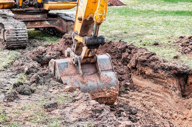 Zbliżenie łyżki koparki na placu budowy Koparka kopie rów pod instalacje podziemne Sprzęt budowlany do robót ziemnych