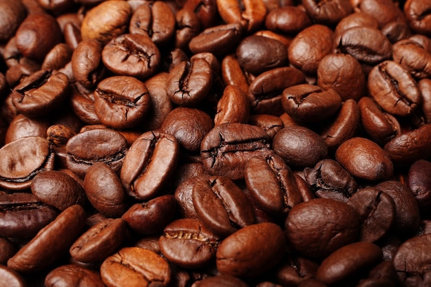 Zbliżenie makro grupa palonych brązowych lub czarnych ziaren kawy w tle