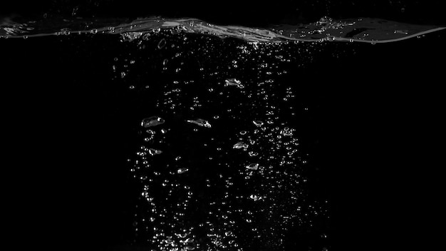 Zbliżenie makro obrazy bąbelków wody sodowej unoszących się do górnej części powierzchni wody, które niewiele